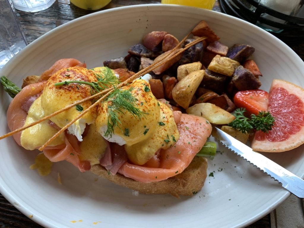 Piatto con uova alla Benedict e patate al forno