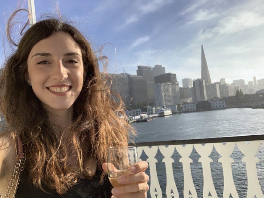 Ragazza con calice di spumante su un traghetto nella baia di San Francisco, con sfondo grattacieli