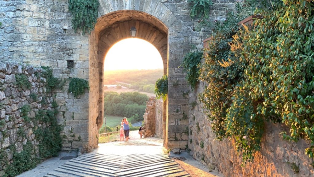 Una delle porte di Monteriggioni da cui si intravede il tramonto sui campi 