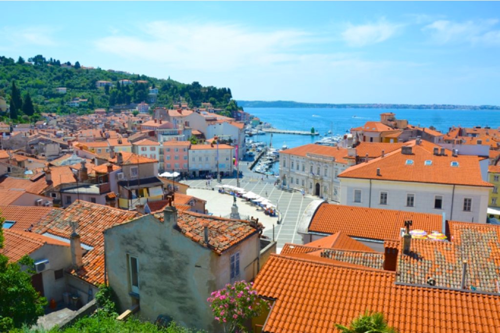 Vista della piazza principale di Pirano dall'alto, con tetti rossi e mare in sfondo