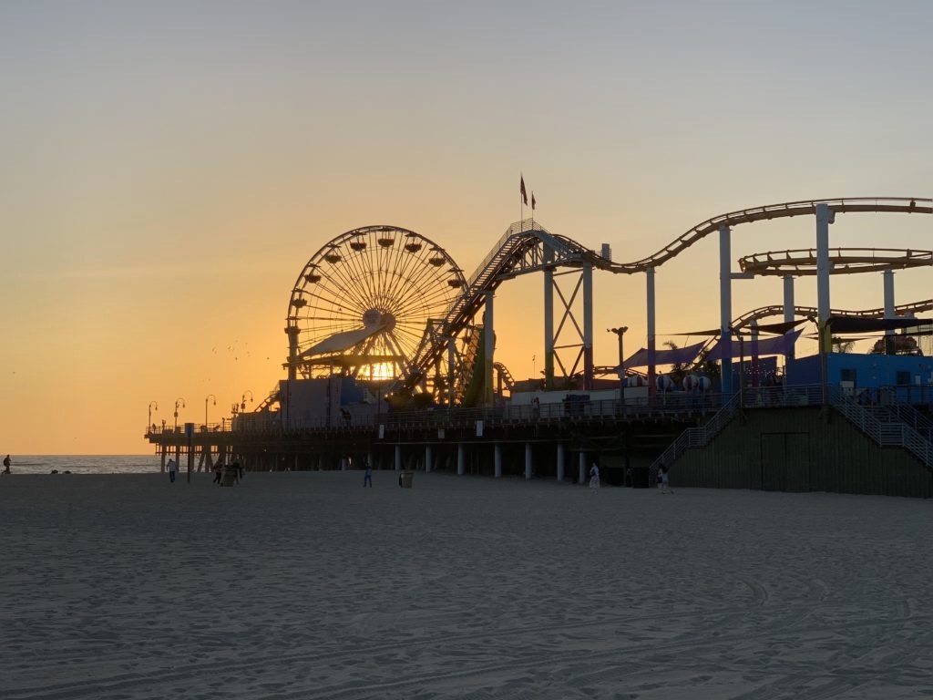 Tramonto sulla spiaggia dietro alla ruota panoramica e alle giostre del Santa Monica Pier