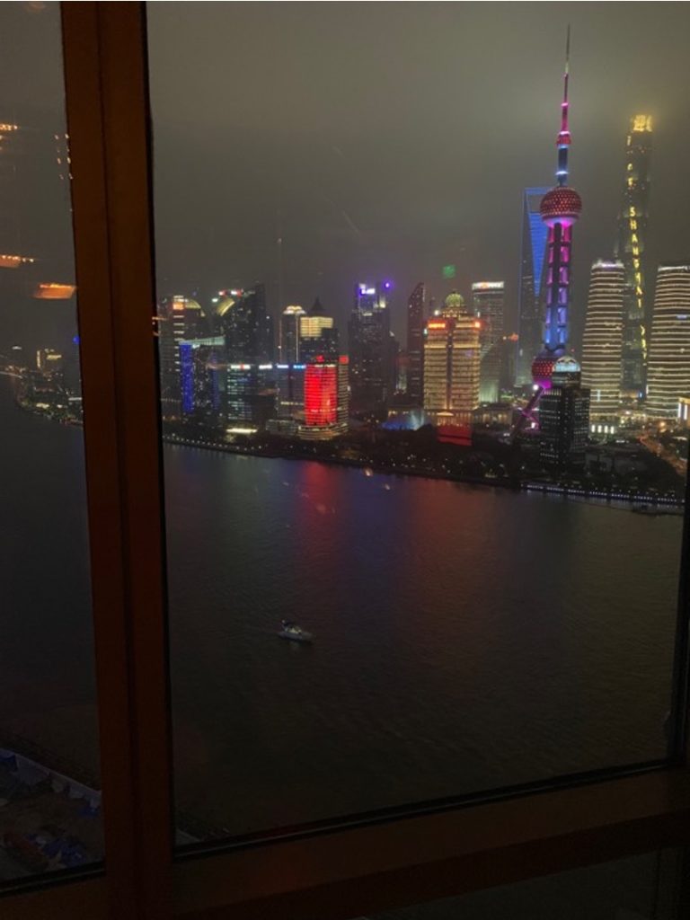 Vista sui grattacieli illuminati di Shanghai da una vetrata di un palazzo