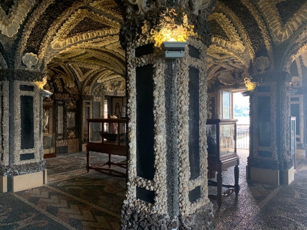 Sala di un palazzo decorata a ricreare delle grotte. Sul fondo, una finestra aperta che si affaccia sul lago
