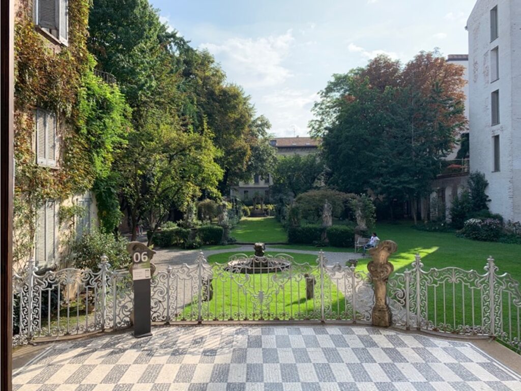 Un balcone che si affaccia su un elegante giardino con alberi e fontana