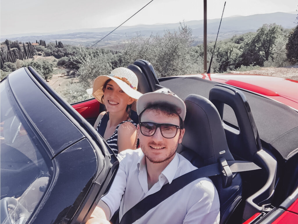 Ragazzo e ragazza in una macchina spider in Toscana