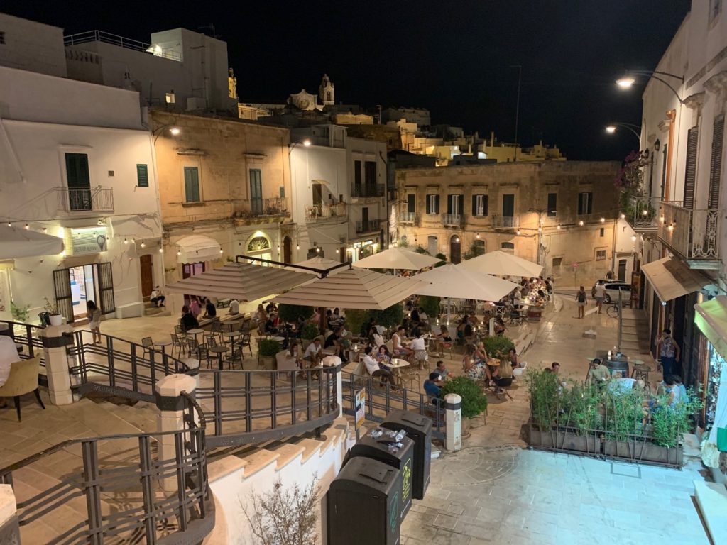 Piazzatta con tendoni e tavolini, di notte